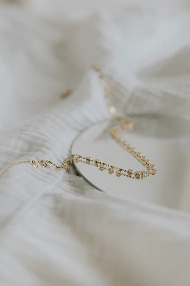 Fine gold necklace arranged on textured white fabric