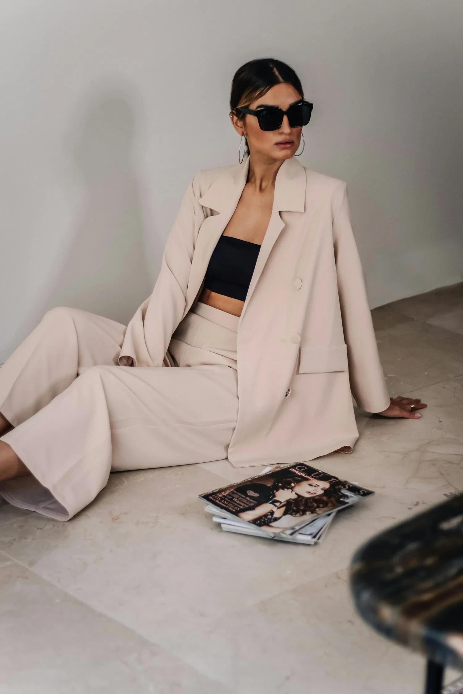 A woman wearing a pale blush blazer and wide-leg trousers with a black top